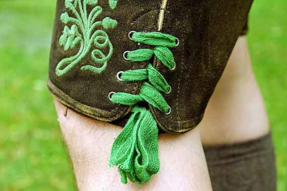 Eine Lederhose mit grüner Schnürung und Knie in Nahaufnahme 