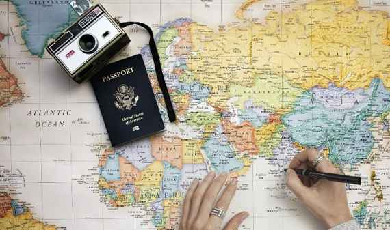 Weltkarte mit Pass, Fotoapparat und Händen