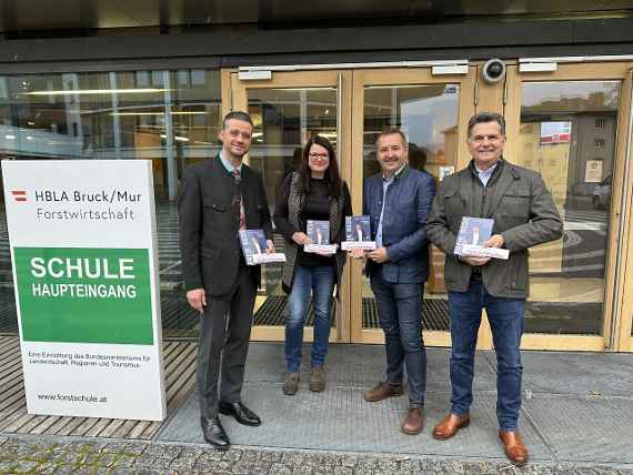 Die Beteiligten vor dem Haupteingang der Schule mit je einem Buch in den Händen