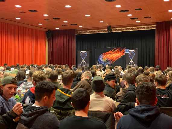 Theater voller Schülerinnen und Schüler mit Blick auf Bühne