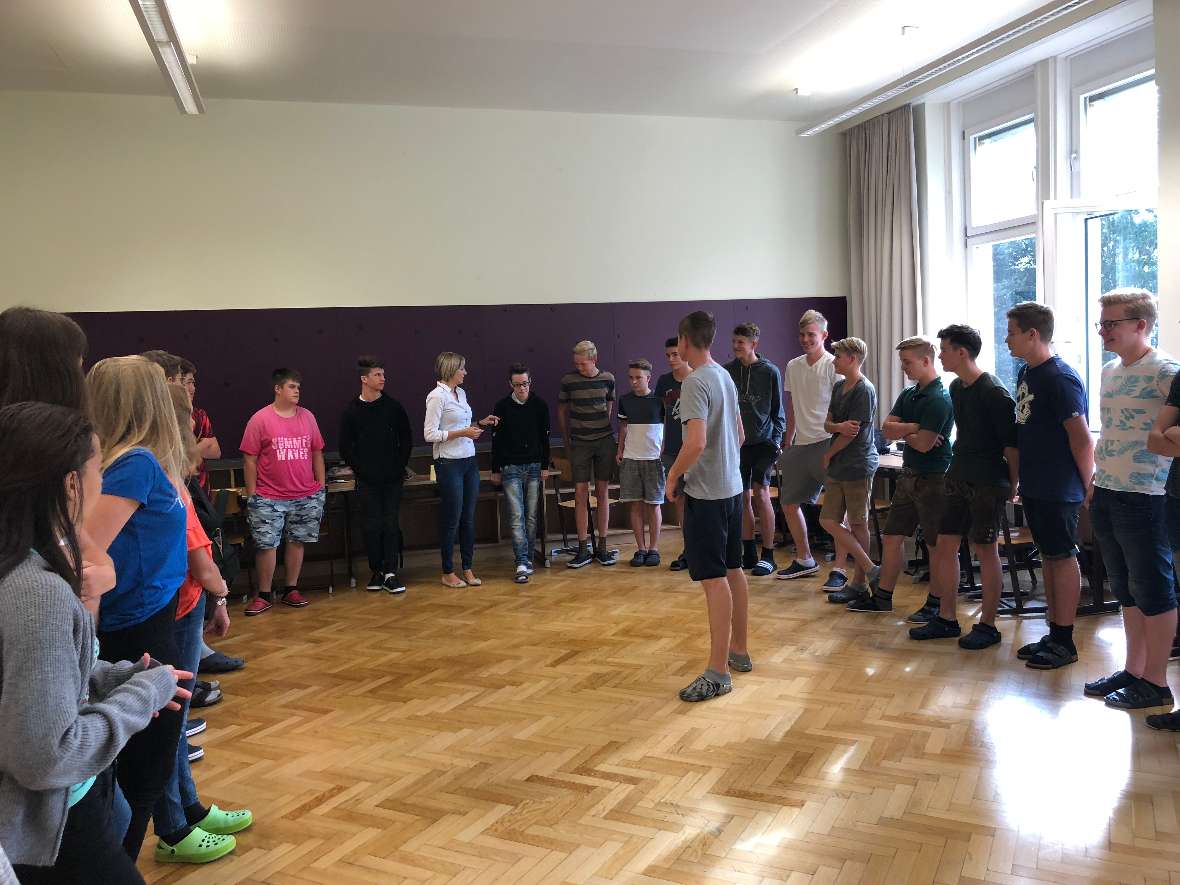 Schülerinnen und Schüler im Halbkreis in ihrer Klasse