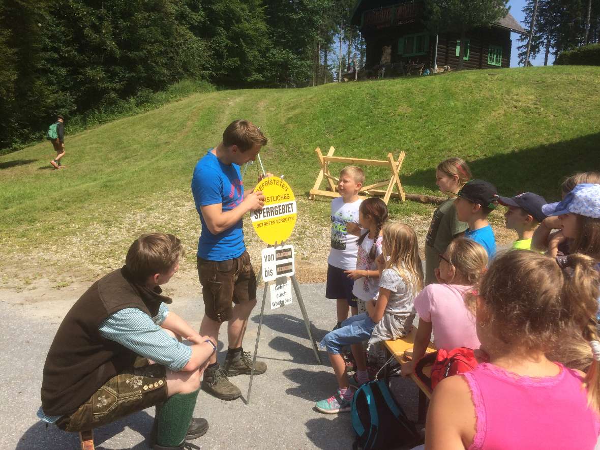 Waldpaedagogen erklaeren Kinder die Gefahrentafel Waldarbeit