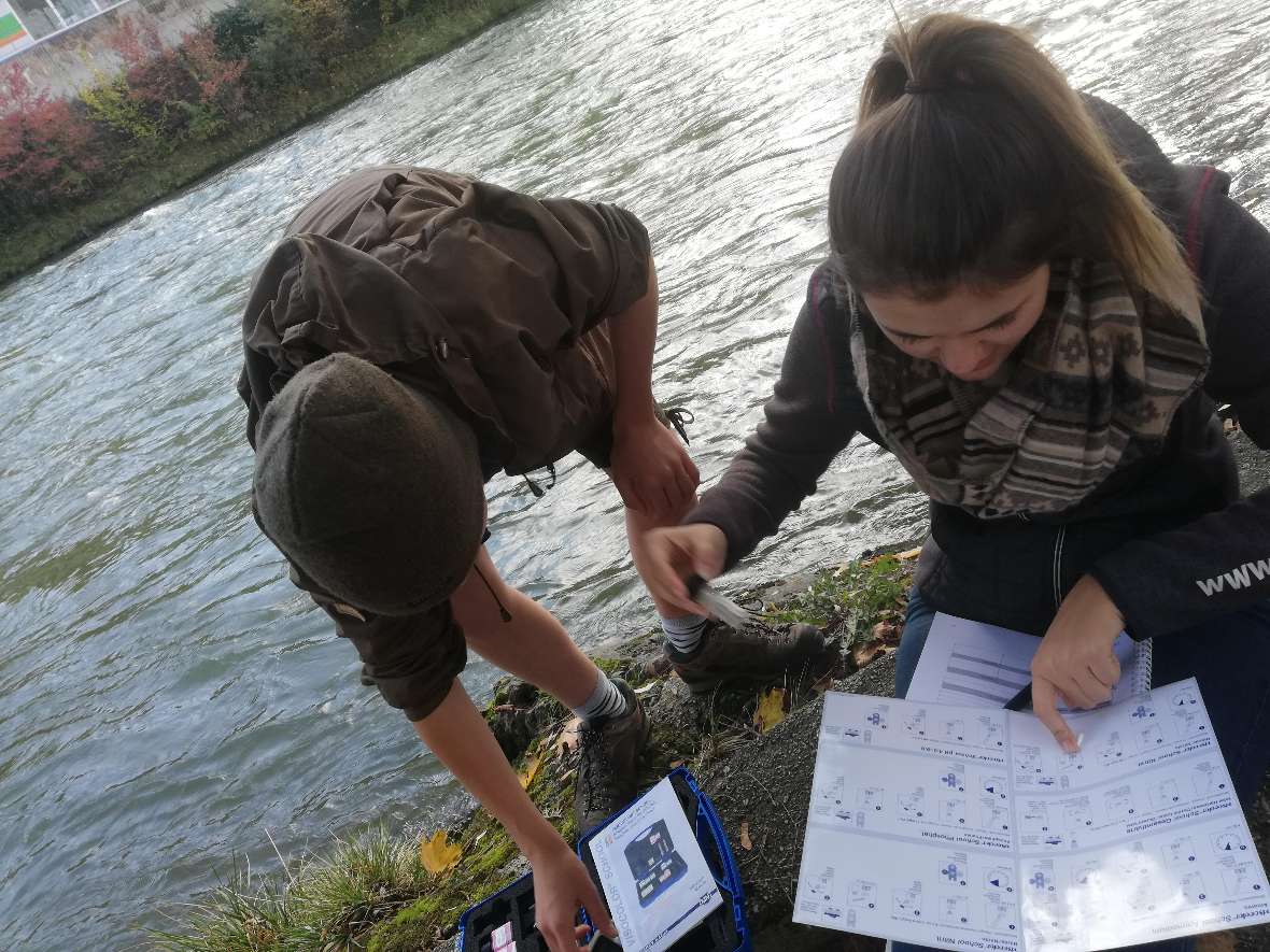 Eine Wasserprobe wird einer Schülerin und einem Schüler verglichen