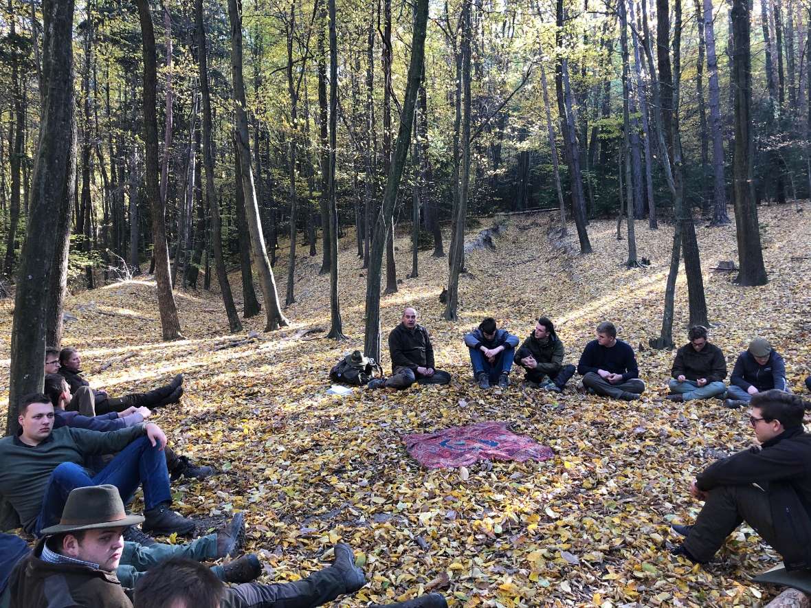 Gruppe sitzt auf dem Waldboden im Kreis