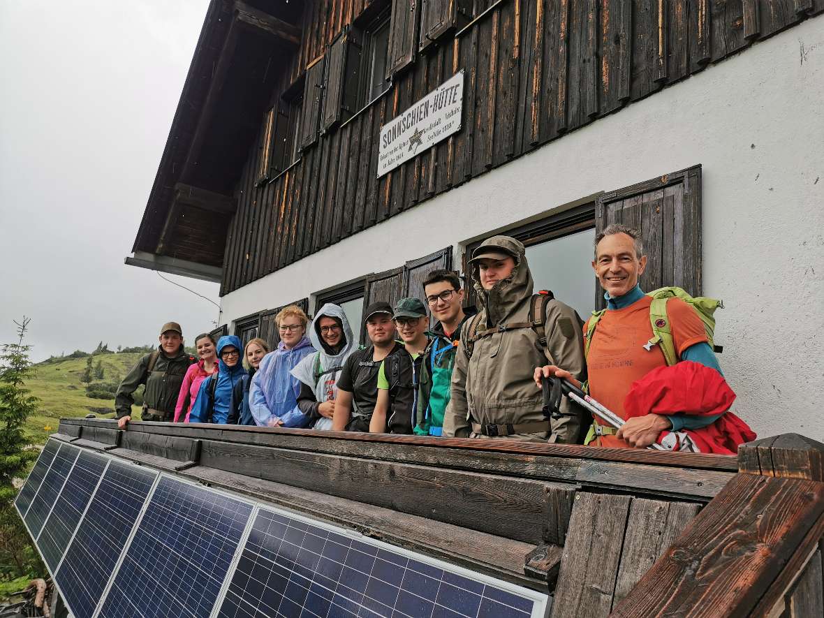 Gruppenbild bei regnerischem Wetter vor Almhütte