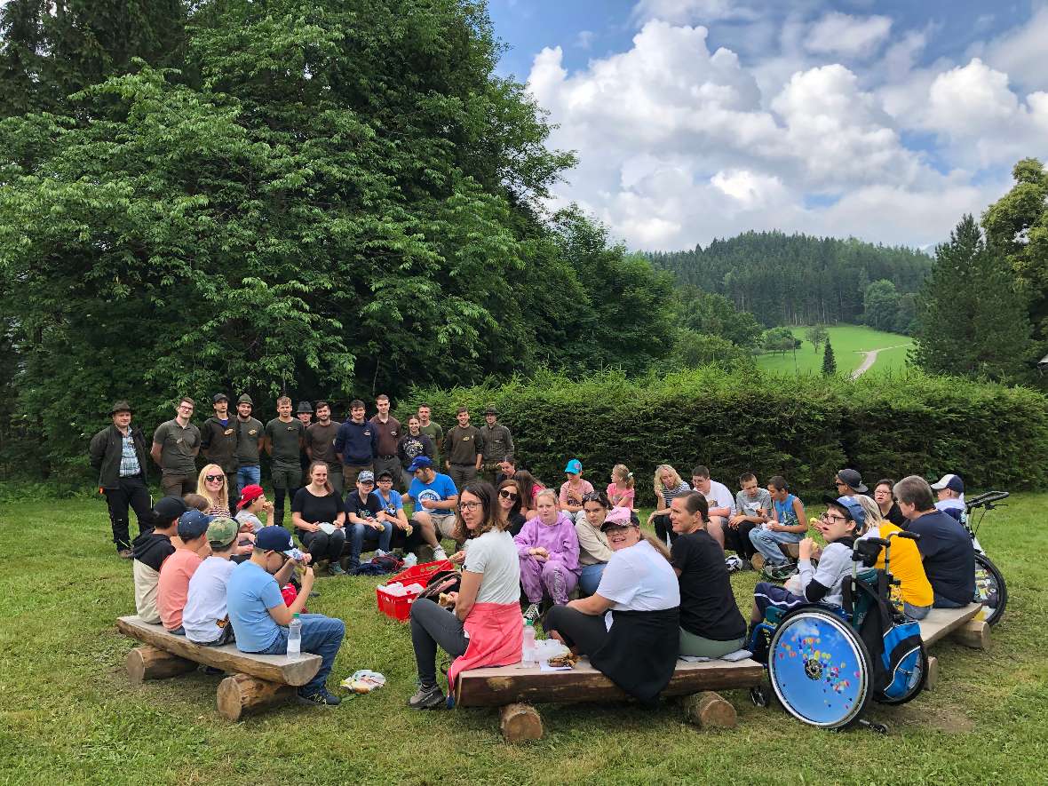 Eine große Gruppe von Kindern und den Waldpädagoginnen und Waldpädagogen im Freien