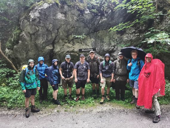 Gruppenbild vor einer nassen Felswand bei Regenwetter